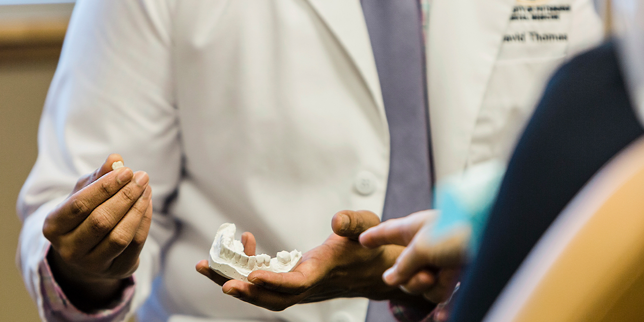 Dentist showing patient dental implant tooth replacement model