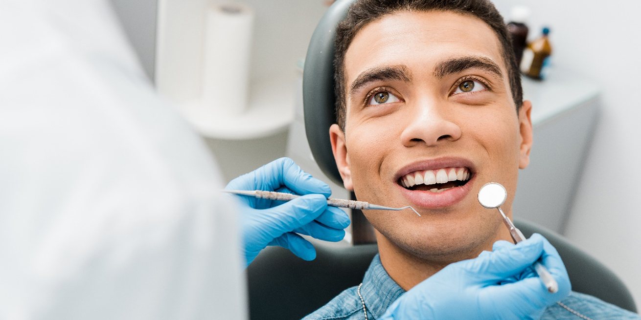 Man in blue shirt looking at dentist about to examine his teeth