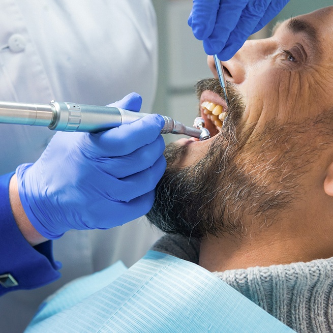 Man in turtleneck sweater undergoing dental cleaning