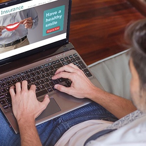 Man looking up dental insurance information on laptop at home