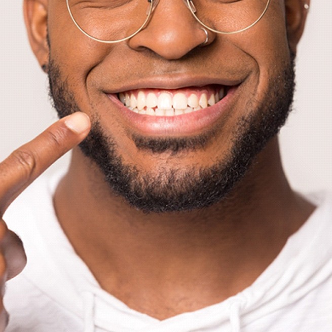 man smiling and pointing to his teeth