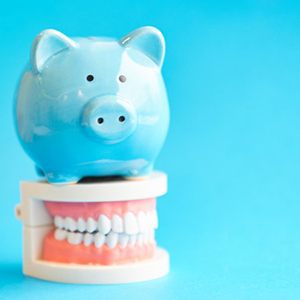 Blue piggy bank sitting on a model of teeth
