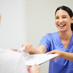 Dental assistant handing a patient dental insurance forms