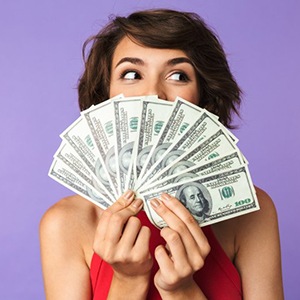 Woman fanning 100-dollar bills over her face