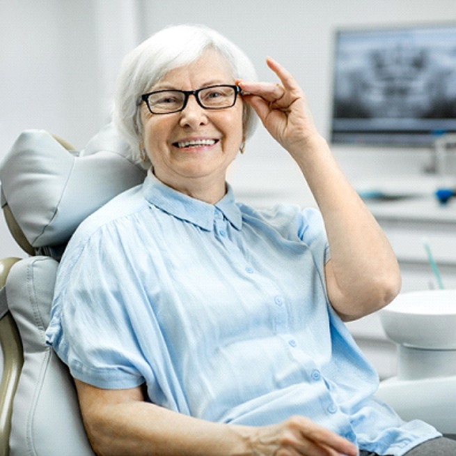 An older woman smiles after learning about proper dental implant care in Burien