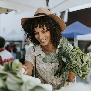 A woman buying fresh vegetables and leafy greens at the market in Burien