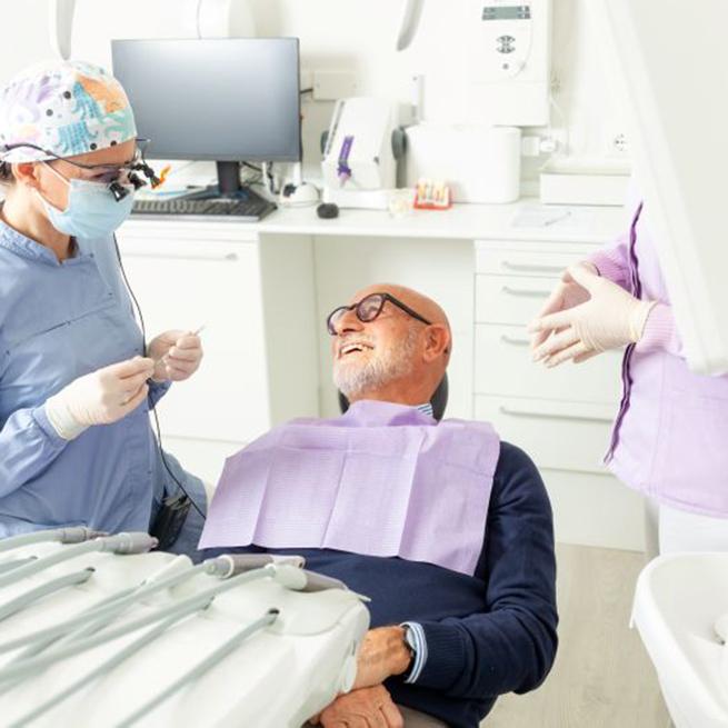 Happy senior patient interacting with his dental team