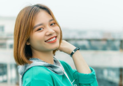 Young woman in teal hoodie smiling outdoors