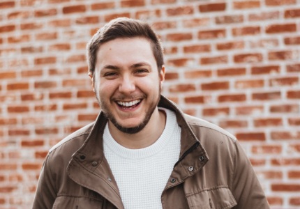 Young man laughing in front of brick wall