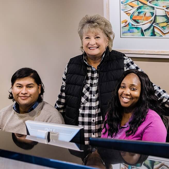 Three dental team members at front desk of dental office in Burien