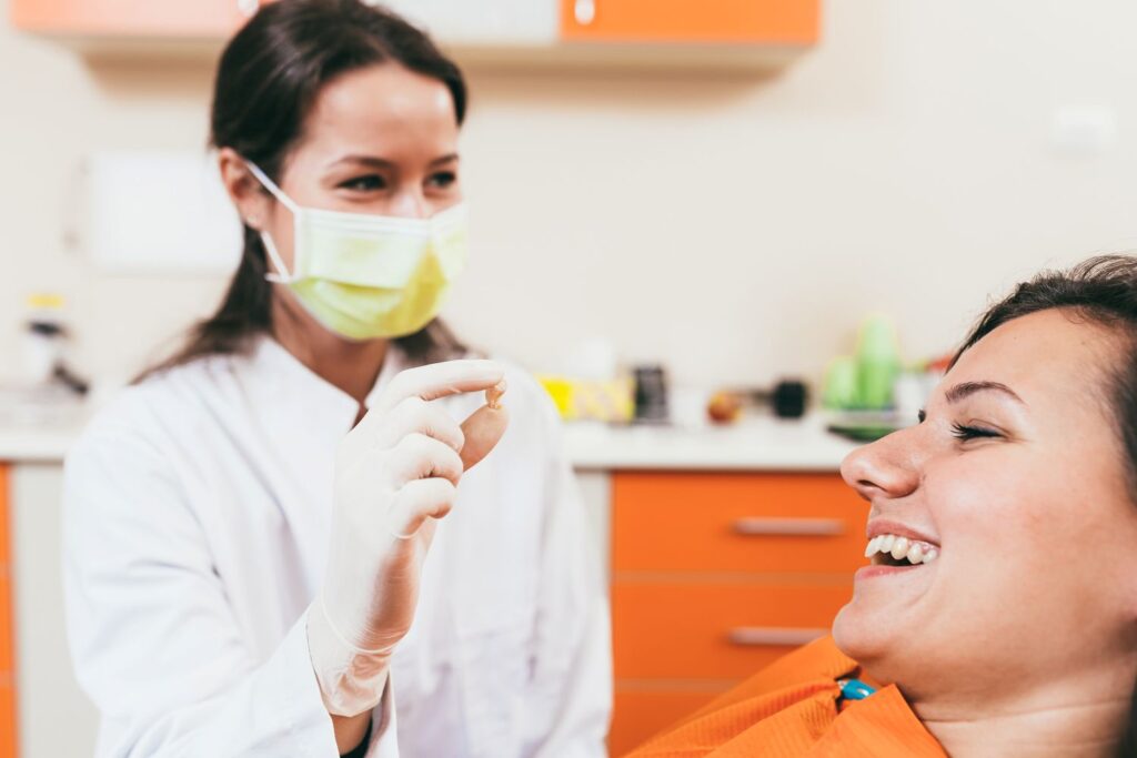 Patient smiling at dentist showing her extracted tooth