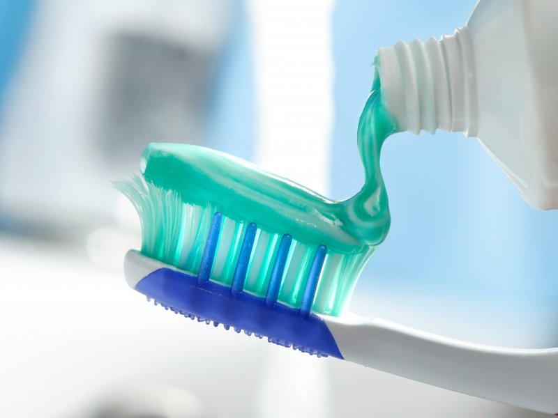 A closeup of toothpaste being applied to a toothbrush