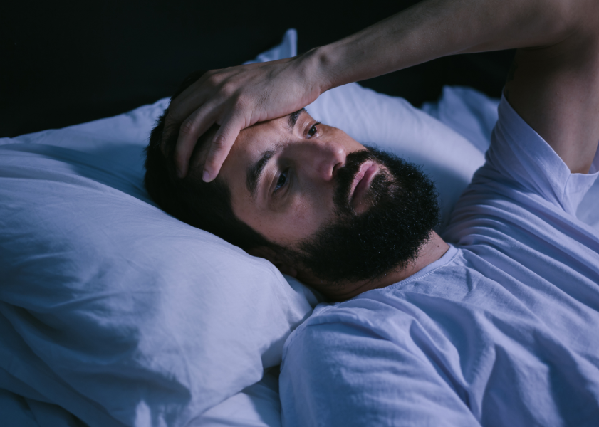 Man lying in bed looking frustrated